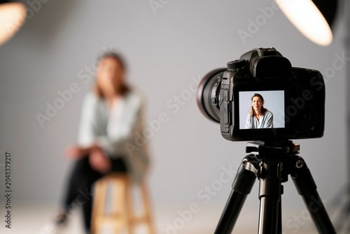 Recording woman in studio, dslr camera on tripod, creating content or capturing video for a vlog