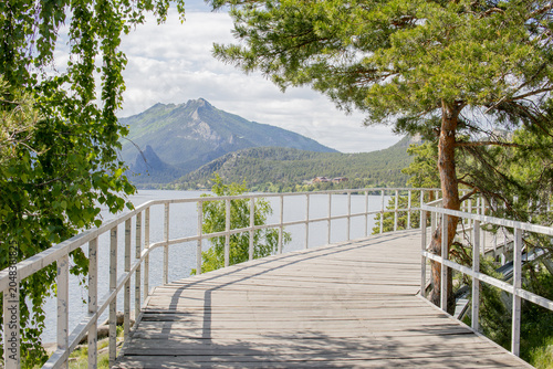 Foto View of lake and mountains among forest with wooden walking path in Borovoe, Kazakhstan