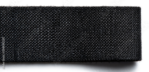 A close-up view presents a segment of dark, tightly woven material, possibly fabric or webbing, with a rough edge. It sits on white