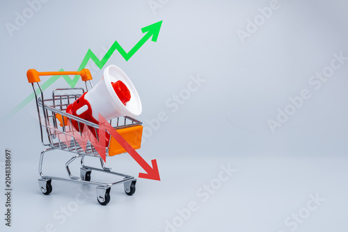 Fényképezés Shopping cart with megaphone and market trend arrows representing e-commerce performance, sales growth and market volatility