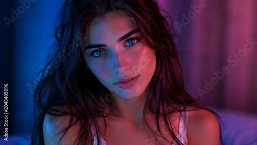 A woman with tousled hair looks at camera under blue and magenta light. Useful for beauty, fashion, music, nightlife, and editorial branding.