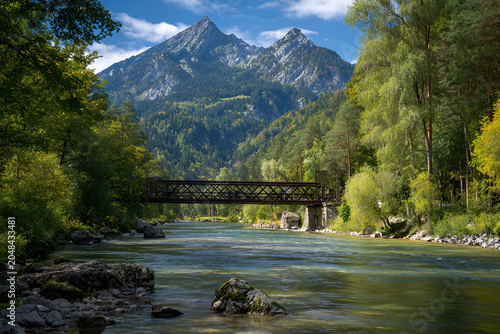A scenic vista showcasing a tranquil river flowing through a lush green landscape towards towering peaks, crossed by a sturdy bridge