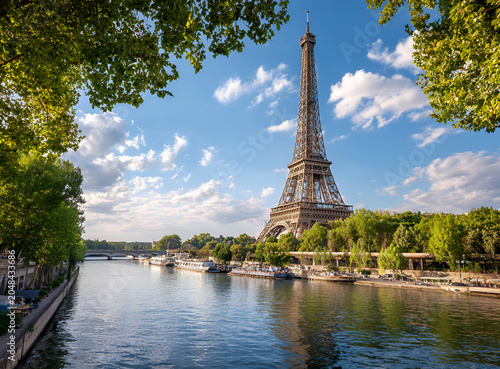 A scenic photo of an iconic metal tower next to a river with boats, framed by lush greenery and a bright blue sky