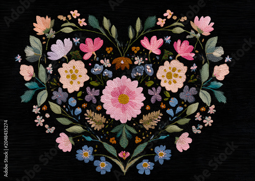 A floral heart arrangement on a black background. Detailed embroidery features varied flowers, leaves, and colors, creating a vibrant, textured design