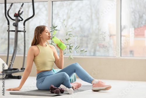 Sporty young woman drinking...