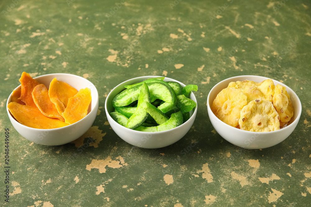 Fototapeta premium Bowls of different dehydrated fruits on green background