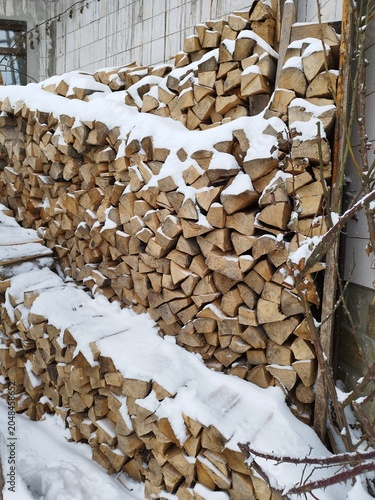 Stack of chopped firewood covered with fresh white snow in winter backyard
