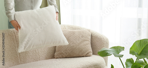 Foto woman arranging white cushion on cozy boucle sofa in bright modern living room w
