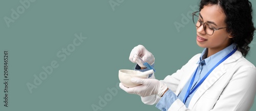 Young African-American female scientist with mortar, pestle and test tube on ...
