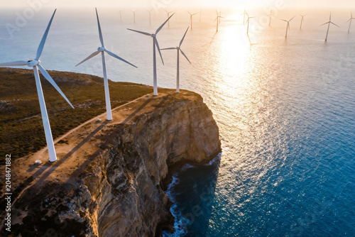 Wind turbines on dramatic cliff edge and offshore wind farm in the ocean at sunset, sustainable green energy infrastructure landscape