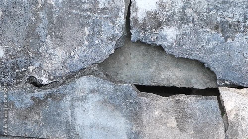 Close-up shot of a cracked and heavily damaged concrete wall with a weathered texture, showing structural wear and decay.