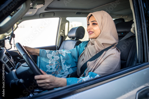 Beautiful woman in Dubai wearing abaya traditional female dress driving the car. Concept about uae and women rights
