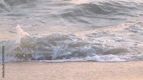 Detailed shot of white foamy sea waves washing over a clean sandy shore, perfect for nature and relaxation backgrounds.