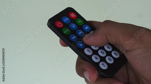 Infrared remote control with colorful buttons being pressed by a human hand, suitable for technology or entertainment concepts.