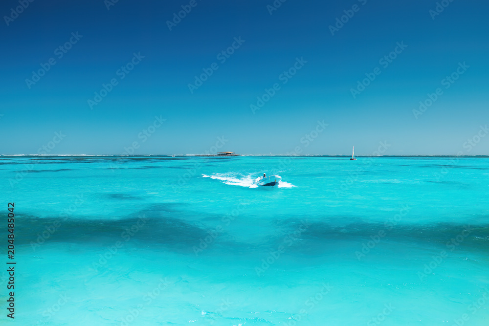 Naklejka premium Motorboat speeding through beautiful turquoise ocean water under a clear blue sky