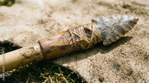 Close-Up Handmade Stone Arrowhead Attached to Wooden Shaft on Rough Fabric