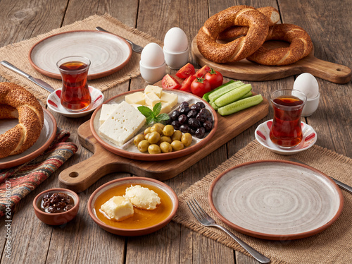 Traditional Turkish Breakfast with Simit, Tea, Cheese, Olives and Honey on Rustic Table
