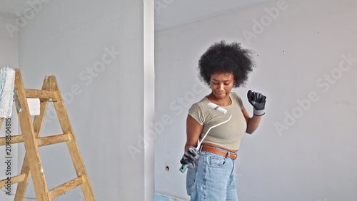 Schilderij op canvas A woman works on home improvement, using a screwdriver to attach a charger to the wall