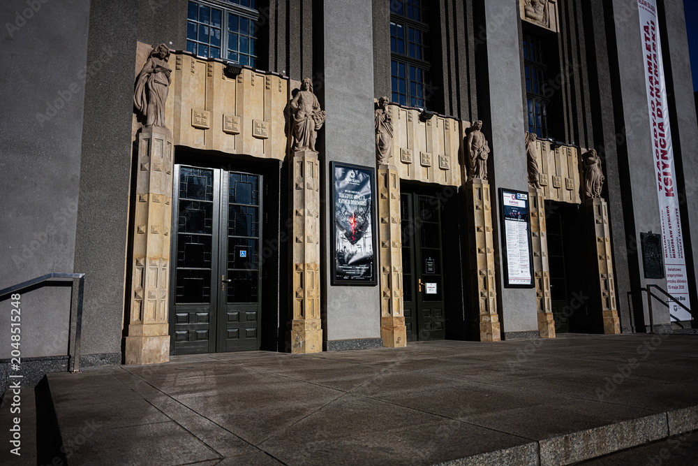Fototapeta premium Art deco theatre entrance with sculpted figures and dramatic shadows in Katowice, Poland