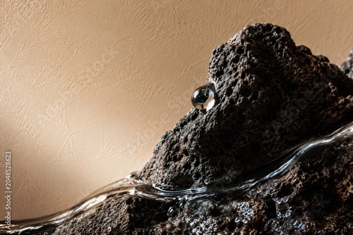 Macro Close-up of Raw Porous Volcanic Basalt Rock with Crystalline Water Drop and Flowing Stream, Minimalist Spa and Beauty Background