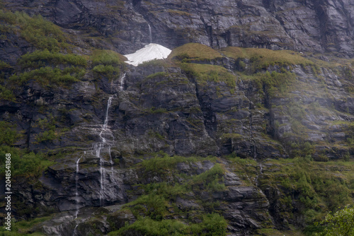 Tableau sur toile Cascading waterfalls and lingering snow patch on misty fjord mountainside, Geira