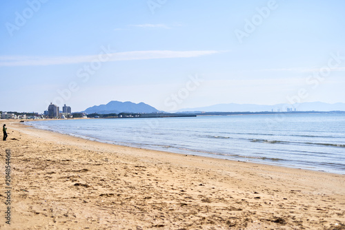 Canvastavla A scenic view of a sandy beach with golden sand stretching along the shoreline under a clear blue sky