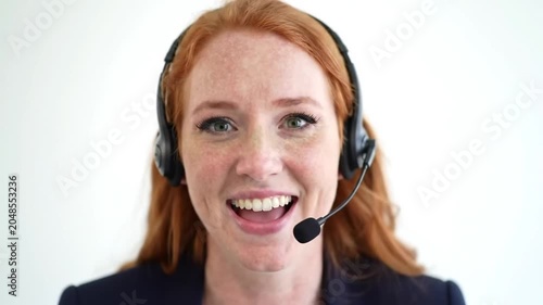 Smiling redheaded woman wearing headset for customer service against white background