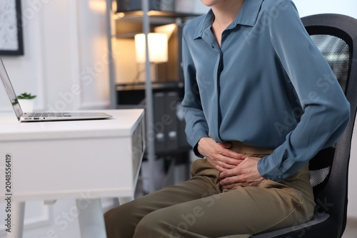 Cuadro en lienzo Woman suffering from menstrual pain at workplace, closeup