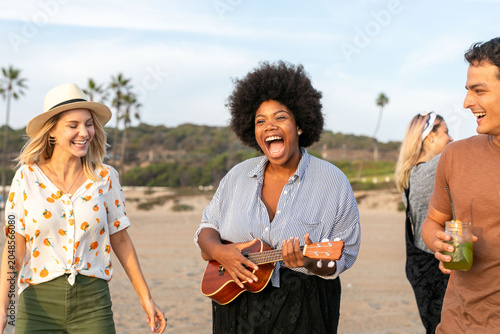 Bild auf Leinwand Joyful friends playing music beachside