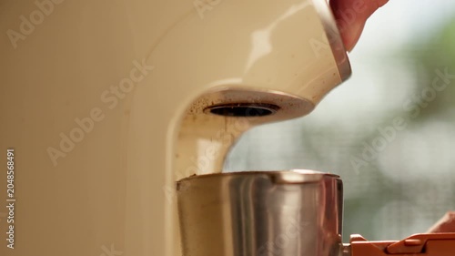 The close-up image shows the coffee grinder being pressed into place, slowly pushing the ground coffee into a coffee bottomless pump. The morning sunlight streams in from behind, creating a warm atmos