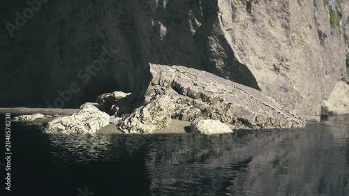 Shadowed limestone inlet with jagged rocks, deep contrasts and textured surfaces, rugged coastal geology, exploratory mood for adventure study and dramatic