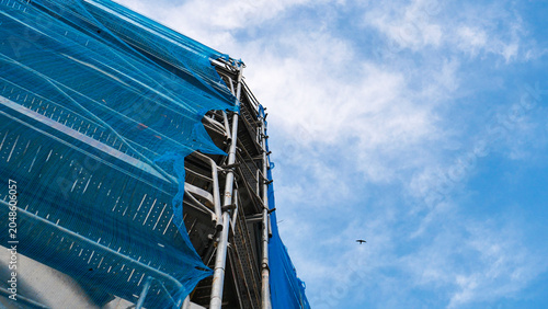 Obraz na płótnie Construction scaffolding with blue safety debris netting on a building site
