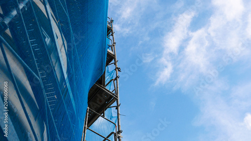 Cuadro en lienzo Construction scaffolding with blue safety debris netting on a building site