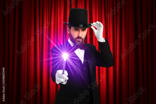 Photography Magician performing trick on stage with red curtains