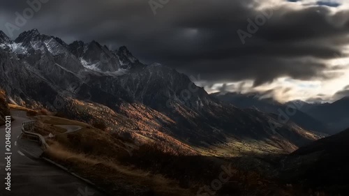 Dramatic mountain landscape under dark clouds and sun rays illuminating peaks