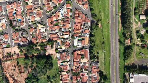 Aerial view of a suburban neighborhood adjacent to a highway and undeveloped land with construction activity