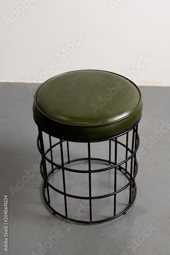 a small green chair stool in the plain room
