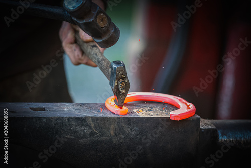 Red hot horse shoe being worked by a farrier. Blacksmith skills. Equestrian. 
