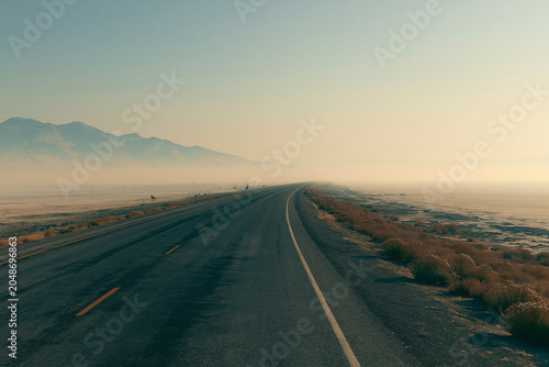 Endless Adventure: Scenic Open Road Across Misty Desert Mountains at Sunset for a Tranquil Road Trip Experience