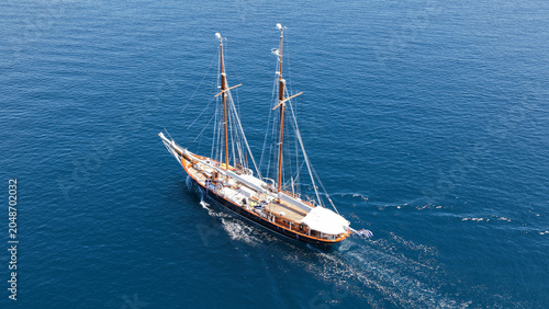 Aerial drone top down photo of classic wooden double mast sailing ship cruising in open ocean sea