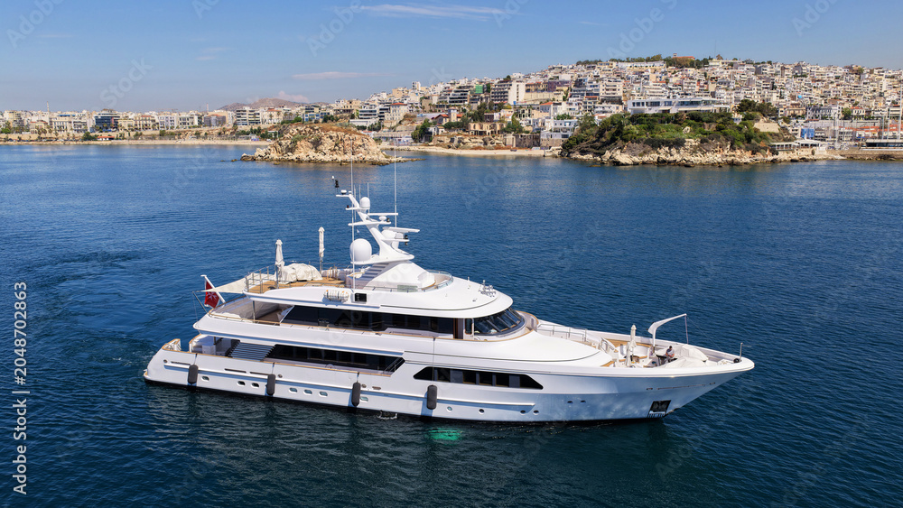Naklejka premium Aerial drone photo of small yacht cruising in low speed near marina and port of Zea or Pasalimani, Piraeus, Attica, Greece