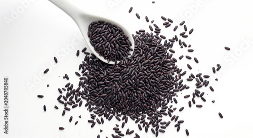 Pile of raw black rice grains scattered on white background