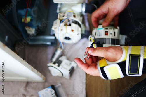 Fotografija Professional handyman repairing a built-in dishwasher, inspecting internal mechanisms and replacing faulty components