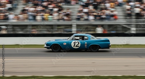 A blue race car speeding on a track with spectators in the background.