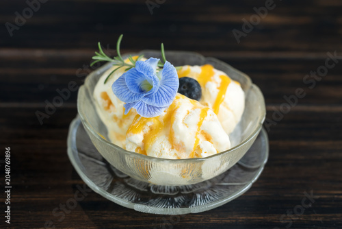 Vanilla ice cream scooped out of container on a bowl with flower.