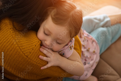 фотографія Toddler cuddling close to mom on a cozy couch, finding warmth, comfort and secur