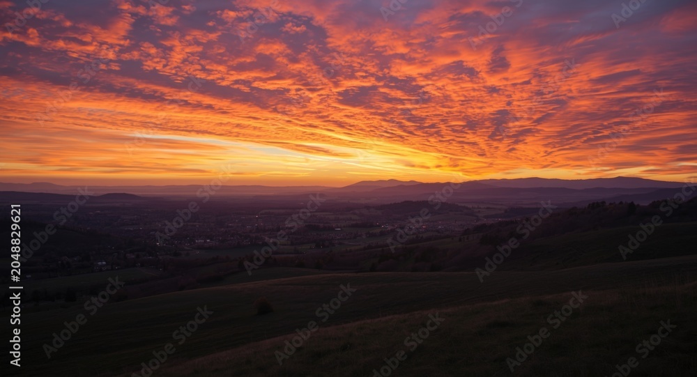 Obraz premium Scenic countryside landscape with distant mountains under colorful sunset sky