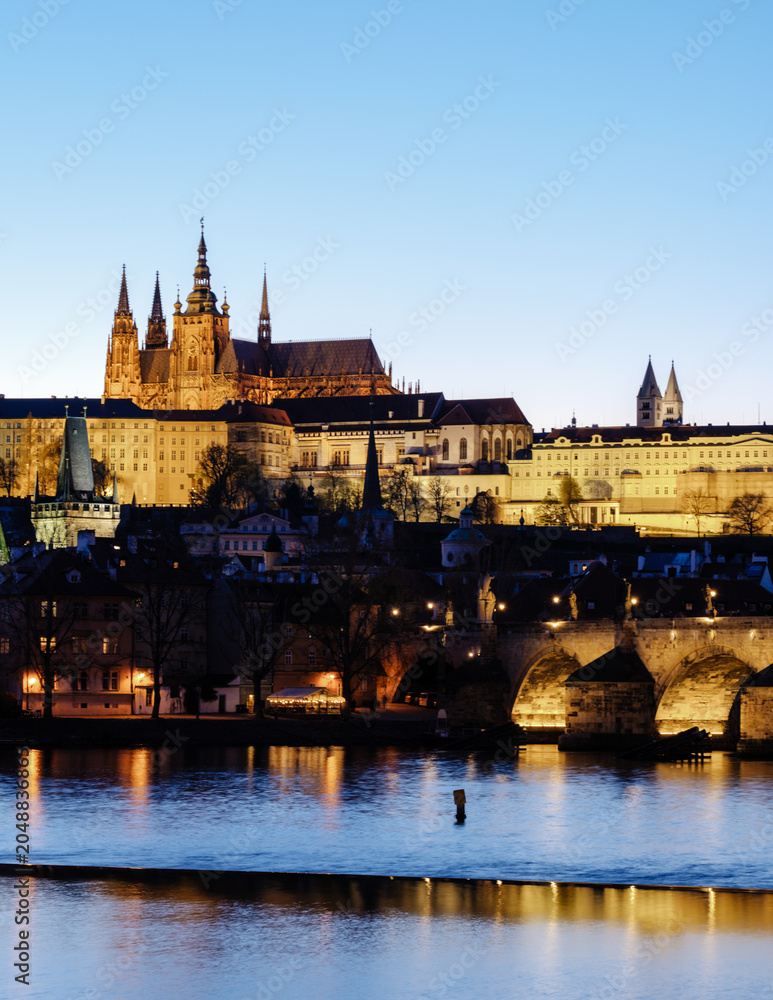 Fototapeta premium Stunning night view of Prague Castle illuminating the Vltava River in Czechia