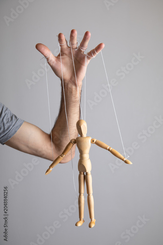 Cuadro en lienzo Man controls the action wooden marionette.