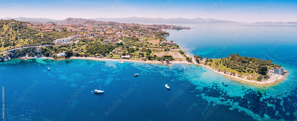 Obraz premium Kusadasi coastal panorama showing Island and city buildings lining the turquoise Aegean Sea with boats on water